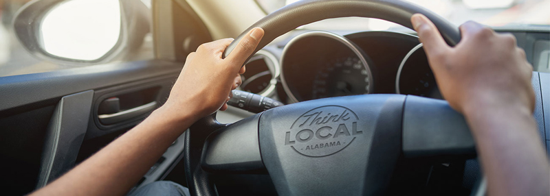 Hands on steering wheel that says, "Think Local"